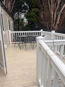 a deck with a table and chairs and a fence at Seton sands caravan rental in Port Seton