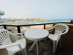 un tavolo bianco e sedie su un balcone con vista sulla spiaggia di R2 Salina Seaview Retreat a Naxxar