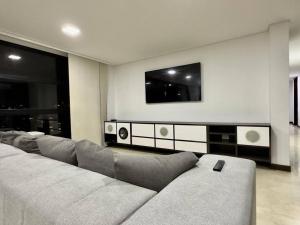 ein Wohnzimmer mit einem Sofa und einem TV in der Unterkunft 1301 Luxury Penthouse, Poblado in Medellín