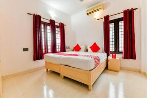 a bedroom with a large bed with red curtains at Ritzy Village Residency in Cochin