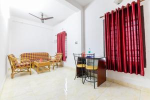 sala de estar con cortinas rojas, mesa y sillas en Ritzy Village Residency, en Kochi