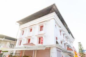 a white building with red windows on a street at Ritzy Village Residency in Cochin