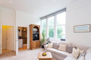 a living room with a white couch and a large window at Charming Studio Apartment Near Clapham Common in London