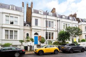 a yellow car parked in front of a white building at Charming Studio Apartment Near Clapham Common in London