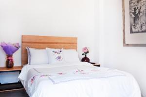 - une chambre avec un lit blanc orné de fleurs dans l'établissement Hospedaje Donaji, à Oaxaca