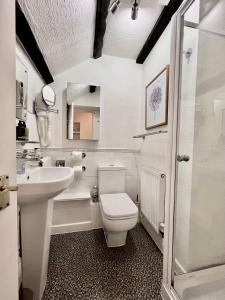 a white bathroom with a toilet and a sink at The Cottage Bed & Breakfast in Polperro