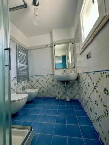 uma casa de banho em azulejos azuis com 2 lavatórios e um espelho. em SIGISHOUSE em Fiumicino
