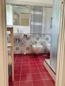 uma casa de banho com 2 lavatórios e piso em azulejo vermelho em SIGISHOUSE em Fiumicino