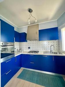 uma cozinha azul com armários azuis e um lavatório em SIGISHOUSE em Fiumicino