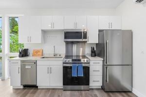 una cocina con armarios blancos y electrodomésticos de acero inoxidable en Martell's Sunspear Sweet Suite en Seattle