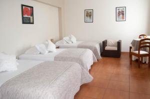 ein Hotelzimmer mit 3 Betten und einem Stuhl in der Unterkunft Aviró Hotel in La Merced