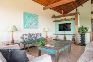 a living room with a table and a tv at Vista panorâmica e praia a pé. in Búzios