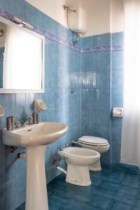 uma casa de banho em azulejos azuis com um lavatório e um WC em B&B il Salvi em Sassoferrato