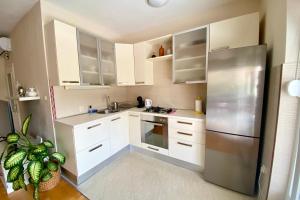 La cuisine est équipée de placards blancs et d'un réfrigérateur en acier inoxydable. dans l'établissement Apartment Nera Zadar, à Zadar