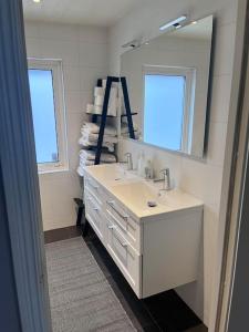 a white bathroom with a sink and a mirror at Villa, Barnvänlig, nära strand/shopping in Halmstad
