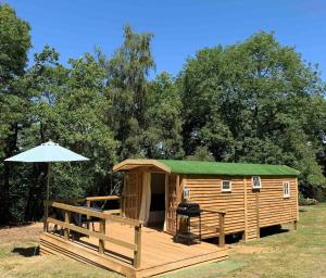 a wooden cabin with a green roof and an umbrella at Jabba The Hut in Sturminster Marshall