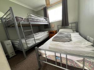 a bedroom with two bunk beds and a window at Bermuda Haven 26, Hemsby - Two bed chalet, sleeps 5, pet free site, onsite entertainment in Great Yarmouth