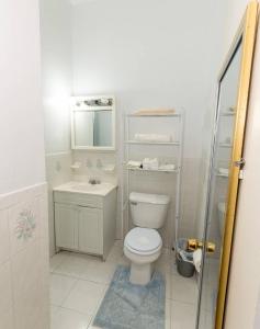 Baño blanco con aseo y lavamanos en Comfortable One Bedroom Apartment en Nueva York