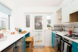 een keuken met witte toonbanken en blauwe kasten bij Chic Urban Retreat with Terrace in Brighton in Brighton & Hove