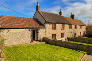 an old stone house with a yard and a fence at Cosy Coastal Retreat-Dog Friendly in Worle