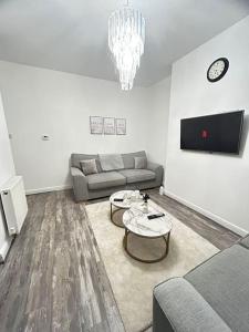 ein Wohnzimmer mit einem Sofa und einem Tisch in der Unterkunft Lovely 5BR Home in Manchester. Close to the City in Manchester