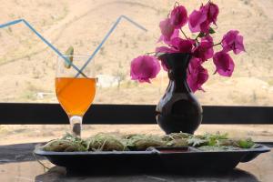 un plato de comida y un jarrón con flores y una bebida en Mount Villa, en Bedla