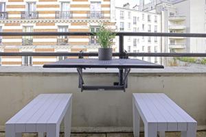 a table and two benches on a balcony with a building at Equerre - Balcony studio near Buttes Chaumont in Paris