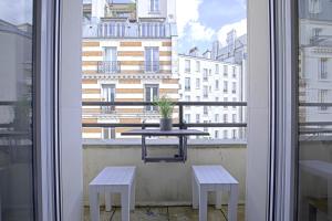 a table on a balcony with two benches and a window at Equerre - Balcony studio near Buttes Chaumont in Paris