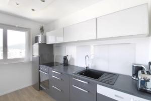 a kitchen with white cabinets and a sink at Studio 4 Swimming pool summer parking & superb view! in Aix-les-Bains