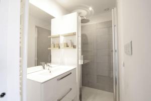 a white bathroom with a sink and a shower at Studio 4 Swimming pool summer parking & superb view! in Aix-les-Bains