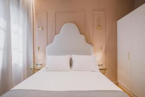 Mantzarou Suites by Corfu Collection في Ágios Rókkos: غرفة نوم بسرير أبيض مع شراشف بيضاء