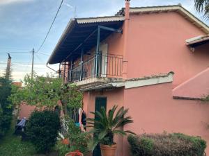 une maison rose avec un balcon latéral dans l'établissement Διαμέρισμα στην Κέρκυρα, à Kanálion