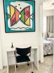een bureau en een stoel in een kamer met een schilderij bij Pérola do Aquarius III in São José dos Campos