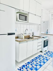 cocina blanca con fregadero y microondas en Pérola do Aquarius III, en São José dos Campos