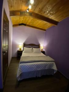 a purple bedroom with a bed and two lamps at Hotel Quinta Vista Verde in Antigua Guatemala