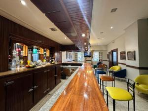 um longo bar de madeira numa cozinha com cadeiras amarelas em Hotel Splendid em Fez