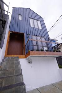 una casa con techo azul, puerta y escaleras en RUMAH BIRU en Bandung