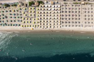 eine Luftansicht auf einen Strand mit Sonnenschirmen und dem Meer in der Unterkunft Suites 33 in Kos-Stadt