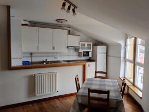a kitchen with white cabinets and a table and chairs at Apartamento Playa de La Atalaya in Ribadesella