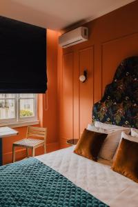 ein Schlafzimmer mit einem Bett mit orangefarbenen Wänden und einem Fenster in der Unterkunft Mantzarou Suites by Corfu Collection in Ágios Rókkos