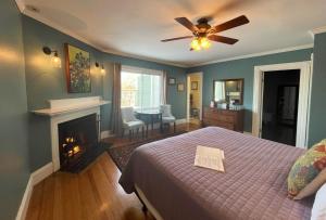 a bedroom with a bed and a fireplace and a ceiling fan at Saltair Inn Waterfront B&B in Bar Harbor