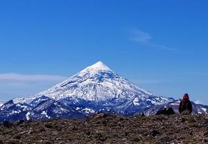 un hombre sentado en una colina con una montaña cubierta de nieve en Cabaña Los Radales, en San Martín de los Andes 9 fotos más