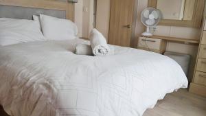 ein weißes Bett mit einem ausgestopften Tier darüber in der Unterkunft Hot Tub Lodge in the Cotswolds - Pet Friendly in South Cerney
