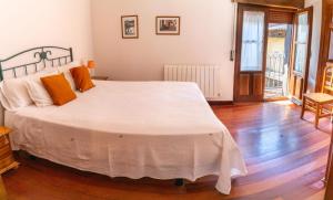 um quarto com uma grande cama branca com almofadas laranja em Casa del tablao em La Alberca