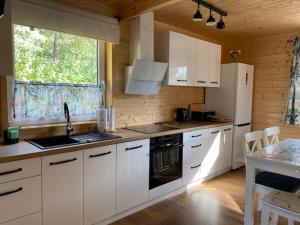 kuchnia z białymi szafkami i dużym oknem w obiekcie Bajkowa Przystań domki nad jeziorem 