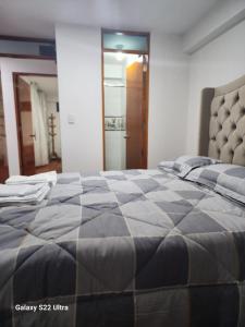 a bedroom with a large bed with a gray comforter at Villa Paraiso Apart in Cusco