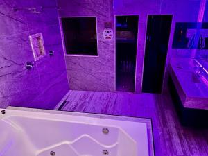 Baño púrpura con bañera y lavabo en Cassino Motel 6 en Santo André