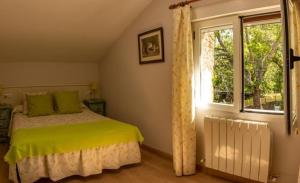 Un dormitorio con una cama con almohadas verdes y una ventana en Casitas Del Huerto, en La Alberca