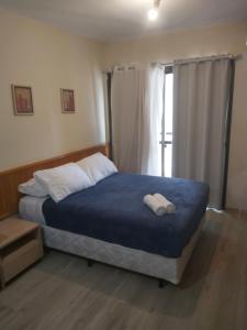 um quarto com uma cama com um cobertor azul e uma janela em M-Flat Hotel Platinum - Paulista em São Paulo