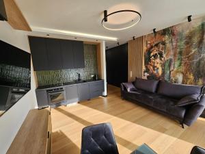 a living room with a leather couch and a kitchen at Apartament Hańcza in Suwałki